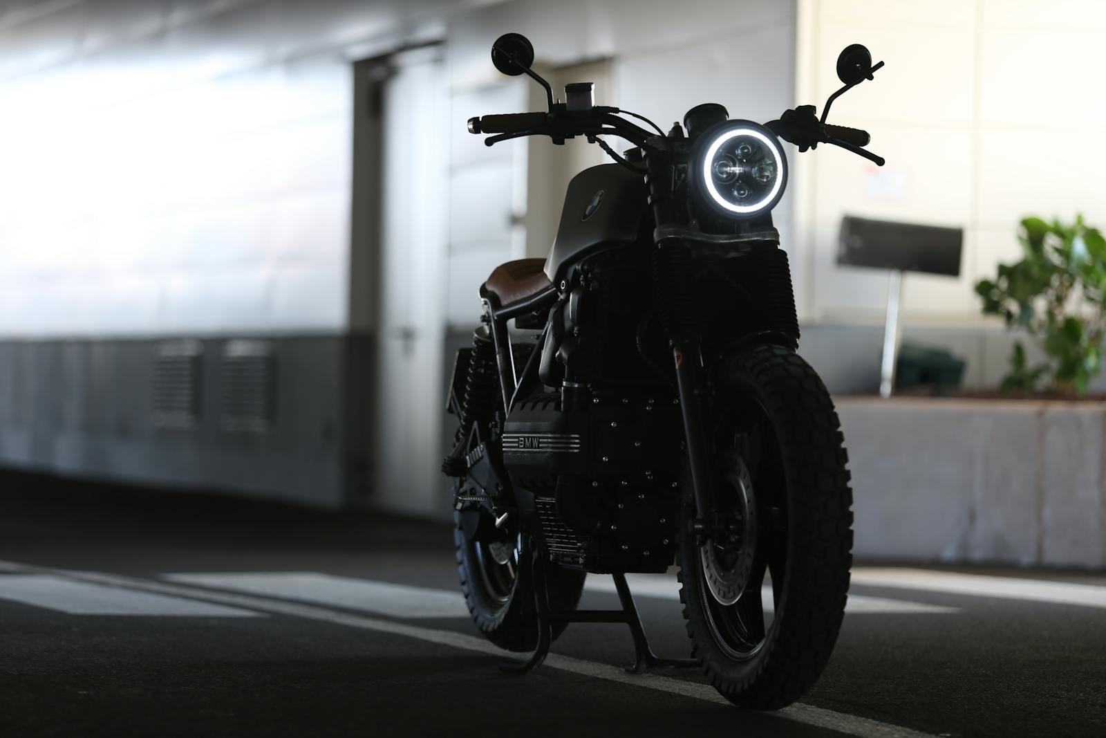 A sleek cafe racer motorcycle parked indoors with strong lighting contrast.